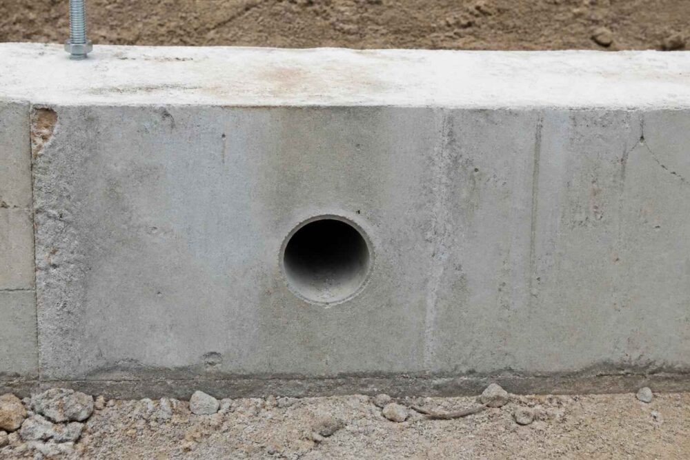 Betonowy mur oporowy z okrągłym otworem odpływowym i żwirowym podłożem