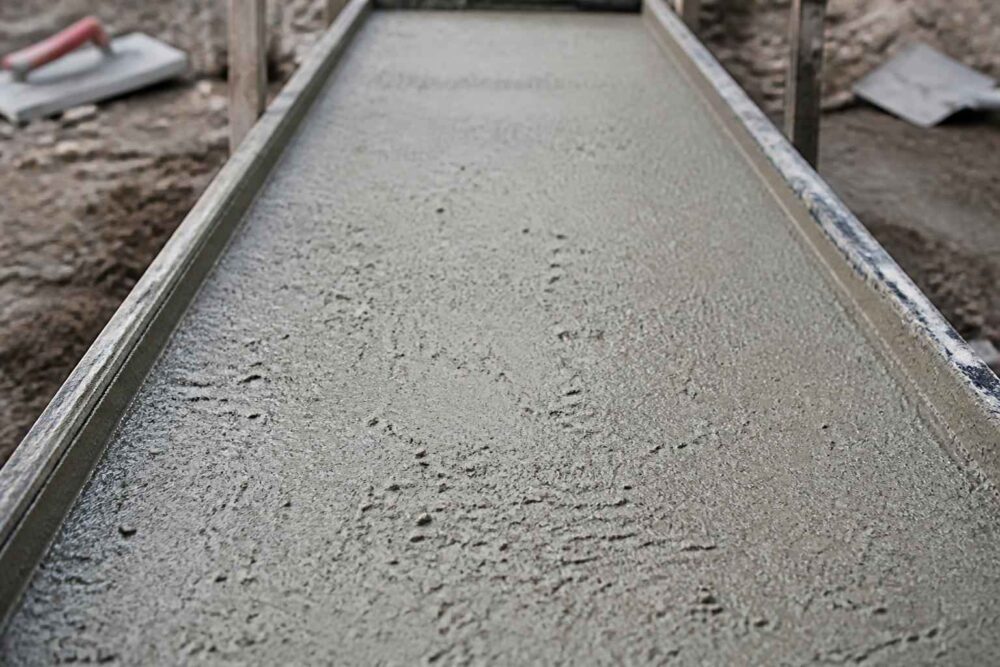 Wyrównywanie świeżej wylewki betonowej Świeży beton wygładzany w długiej drewnianej formie budowlanej